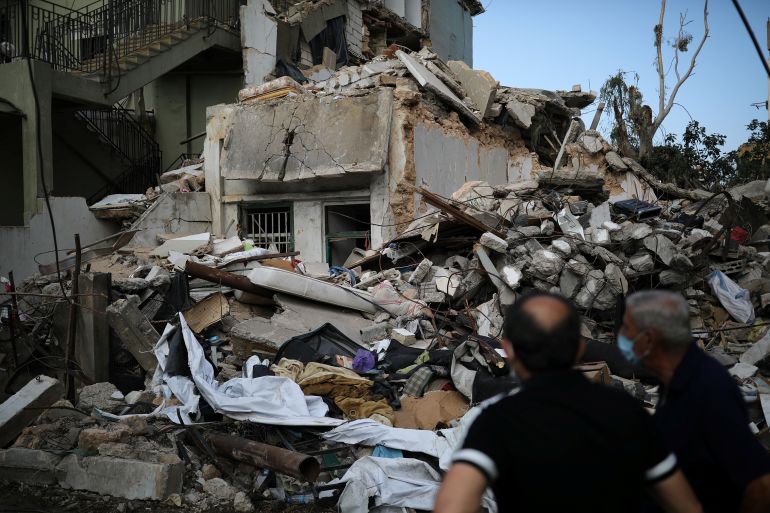 Locals look at a destroyed house where the wife and two of the daughters of Syrian refugee Ahmed Staifi were killed following a massive explosion, in Beirut