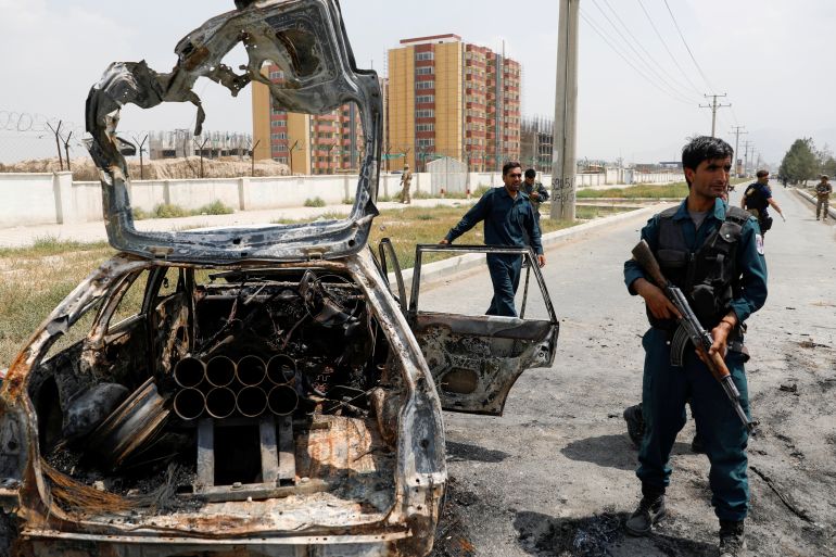 Afghan police officers inspect a vehicle from which insurgents fired rockets, in Kabul