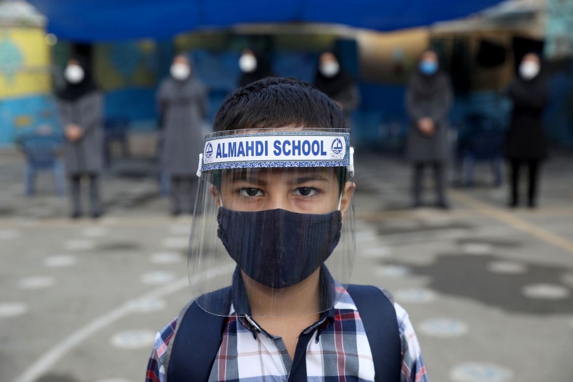 A student wearing a protective face mask and shield to help prevent the spread of the coronavirus disease (COVID-19), looks on as he poses for a picture at Al-Mahdi school in Tehran