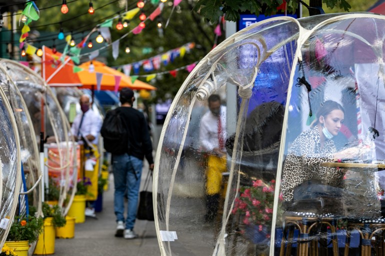 A woman sits outside Cafe Du Soleil under bubble tents