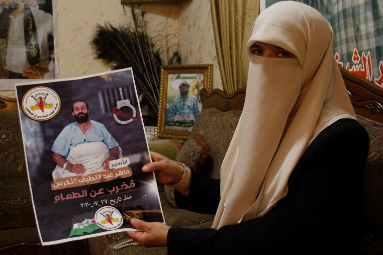 زوجة الأسير ماهر الأخرس تحمل صورته داخل منزلها في لقاء سابق قبل اسبوعين خلال زيارة الجزيرة نت لها