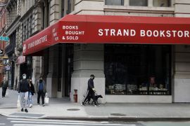 epa08412510 People wearing masks walk past the STRAND bookstore in the East Village area of New York, USA, 09 May 2020. The Strand bookstore in Manhattan is one of the worldÕs largest bookstores and has become a cultural landmark since it opened...