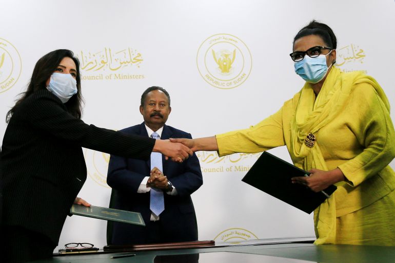 Acting Minister of Finance and Economic Planning, Heba Mohammed Ali shakes hands with Mai Abdelhalim, General Electric Co. Executive director for the regional representative office for Africa and East Mediterranean district after signing a memorandum of understanding as Sudanese Prime Minister Abdalla Hamdok looks on in Khartoum, Sudan October 15, 2020. REUTERS/Mohamed Nureldin Abdallah