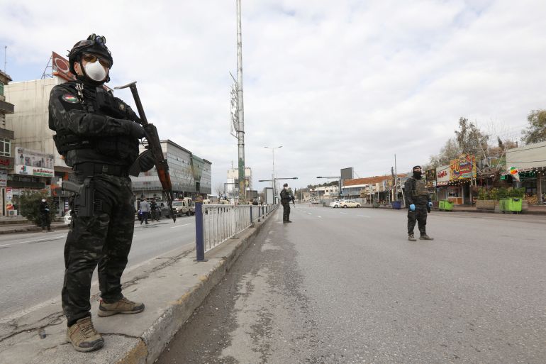 Security men stand in an empty street during a curfew imposed by Iraqi Kurdish authorities, following the outbreak of coronavirus, in Sulaimaniya