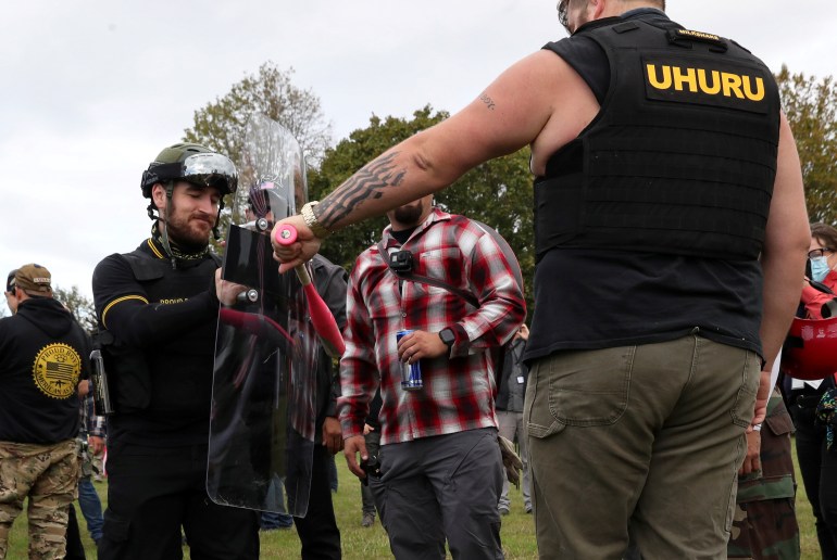 A man tests a shield with a baseball bat as people gather for a rally of the far right group Proud Boys, in Portland