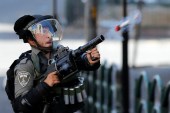 شرطي إسرائيلي يطلق عبوة غاز مسيل للدموع على الفلسطينيين في الضفة الغربية المحتلة (رويترز)