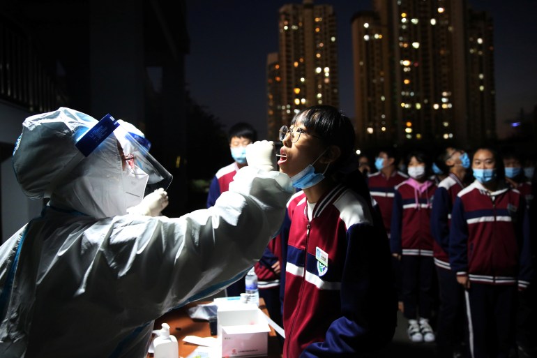 Medical worker collects a swab from a student for nucleic acid testing in Qingdao