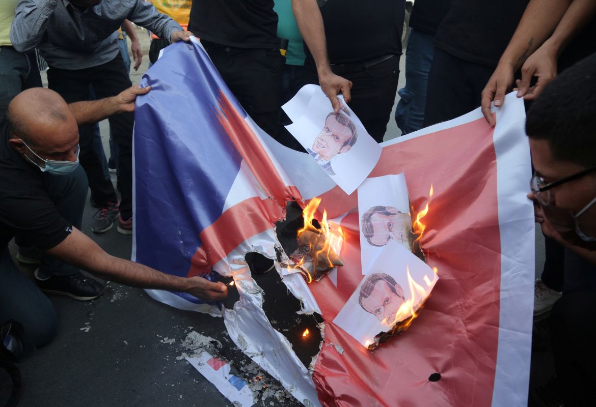 Iraqi people burn a French flag during a protest against the publications of a cartoon of Prophet Mohammad in France and French President Emmanuel Macron's comments, outside the French embassy in Baghdad