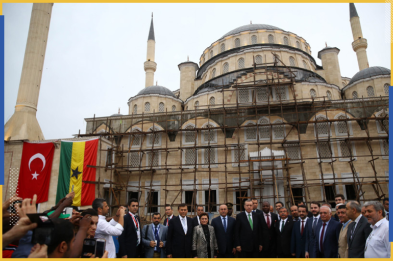 صورا بجانب بعض مواطني الجالية ومن خلفه العَلَمين التركي والغاني.