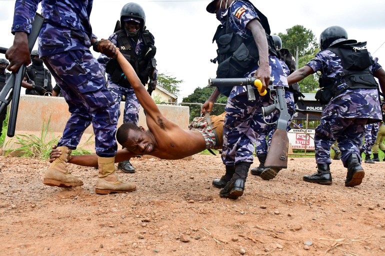 Ugandan riot policemen detain a supporter of presidential candidate Robert Kyagulanyi, in Luuka district