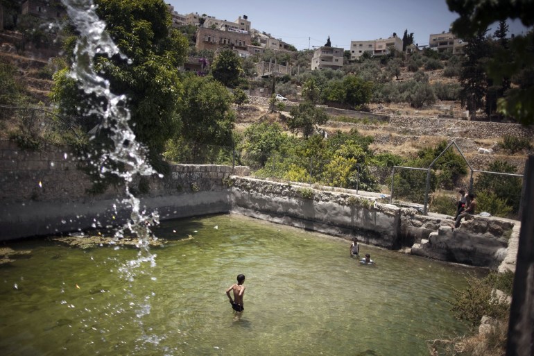 Palestinian children swim in the ancient spring in the West Bank village of Battir, located between Jerusalem and Bethlehem, on June 17, 2012, where eight families take daily turns watering their crops from the natural spring. The effort by the Palestinian authorities to ask UNESCO to recognize the village of Battir as a World Heritage site and prevent the construction of the separation fence has been bogged down by internal Palestinian disagreements, designs and interests as the formal submission of the case was blocked at the last minute. AFP PHOTO/MENAHEM KAHANA