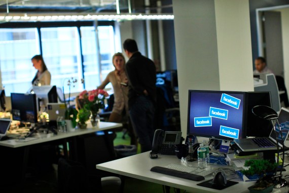 Facebook workers stand at their desks before a news conference at their office in New York