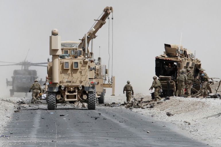 U.S. troops assess the damage to an armoured vehicle of NATO-led military coalition after a suicide attack in Kandahar province