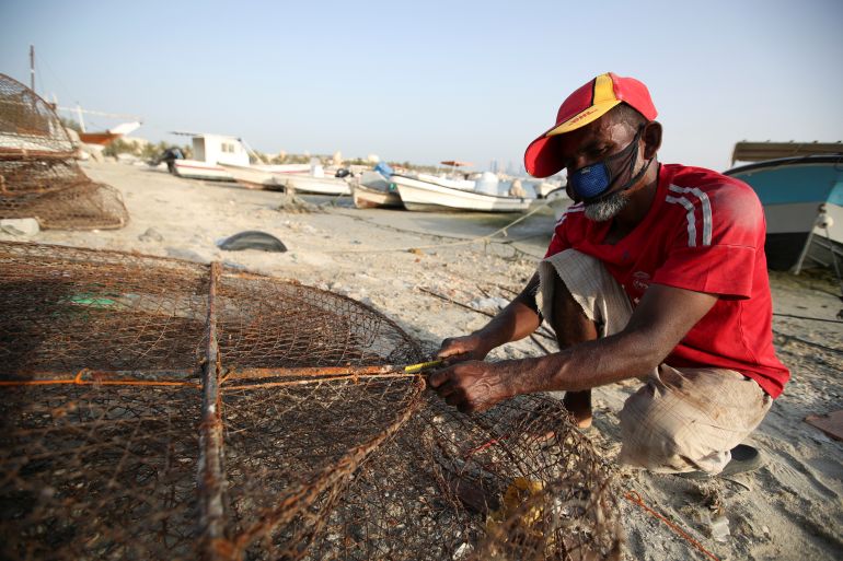 A fisherman wearing a face mask prepares his fishing cage, at a fishing harbour port, following the outbreak of the coronavirus disease (COVID-19), in Manama