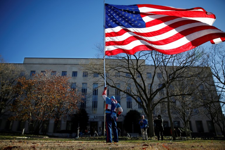 Demonstrator flies a U.S. Flag after former national security adviser Flynn arrived for sentencing at U.S. District Court in Washingto