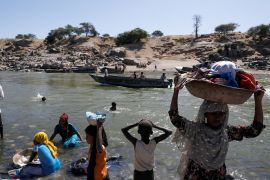 Refugees stand on the Ethiopian bank of a river that separates Sudan from Ethiopia near the Hamdeyat refugees transit camp