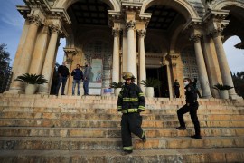 Israeli police and firefighters stand outside the Church of All Nations next to the Garden of Gethsemane after a man tried to set a fire inside the Church
