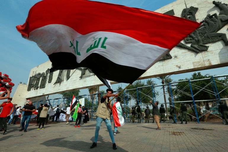 Anti-government demonstration in Iraq- - BAGHDAD, IRAQ - NOVEMBER 08: A demonstrator waves a large Iraqi national flag during an anti-government demonstration over corruption and poor services in Tahrir Square in the centre of Iraq's capital Baghdad on November 08, 2020.
