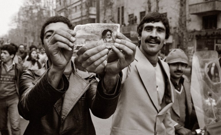 مواطنان إيرانيان يمزقان صورة الشاه من عملة ورقية ويلصقان صورة الخميني عيلها (الصحافة الإيرانية)