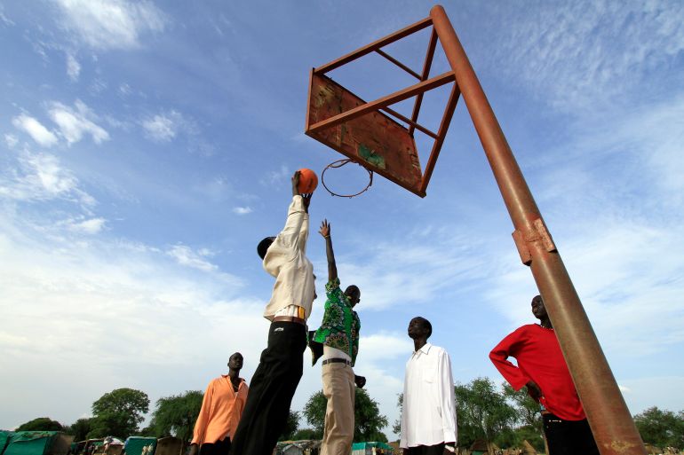 A basketball team plays a game before the arrival of the body of Sudan-born NBA star Manute Bol in the town of Turalei