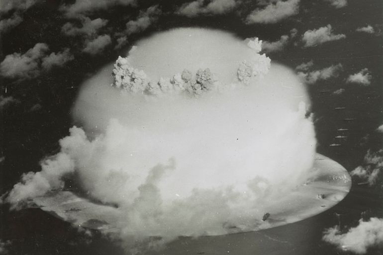 Handout of a mushroom cloud rises with ships below during Operation Crossroads nuclear weapons test on Bikini Atoll