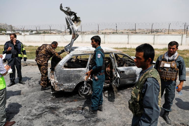 Afghan police officers inspect a vehicle from which insurgents fired rockets, in Kabul