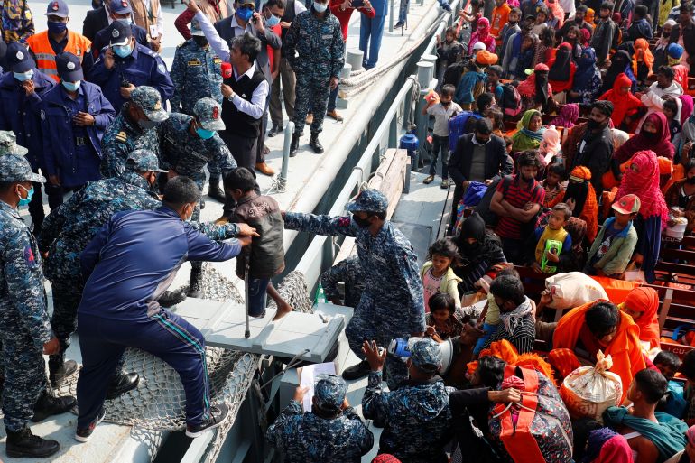 Bangladesh Navy personnel help a disabled Rohingya refugee child to get off from a navy vessel as they arrive at the Bhasan Char island in Noakhali district