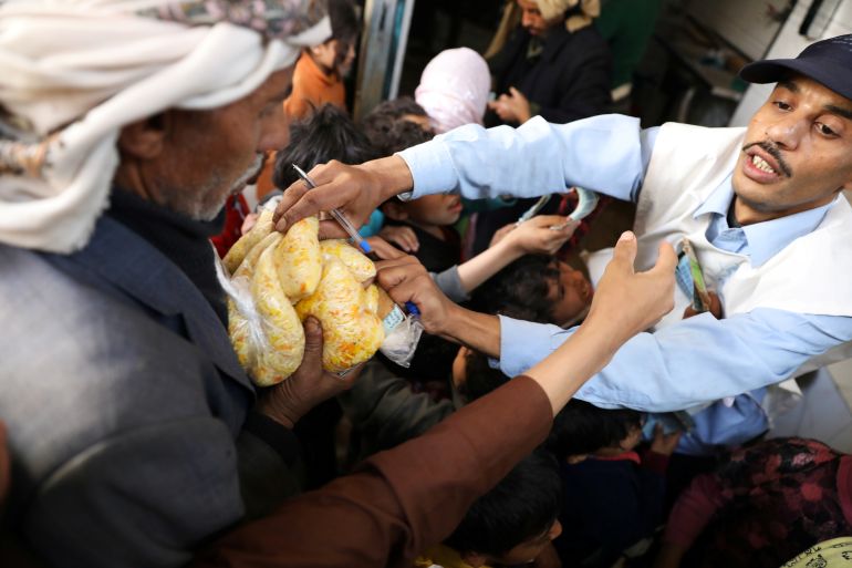 People gather outside a charity kitchen to get food donations in Sanaa
