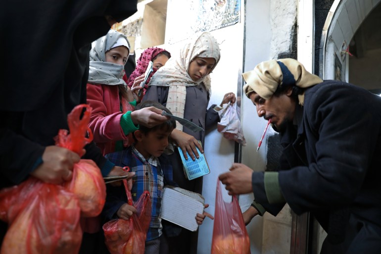 A woman and children receive food donations from a charity kitchen in Sanaa