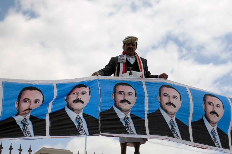 A supporter of Yemen's President Ali Abdullah Saleh holds posters of Saleh during a rally in Sanaa