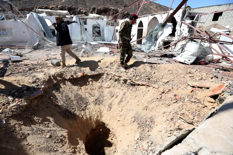 Government soldiers walk at the site of a Houthi missile attack on a military camp's mosque in Marib