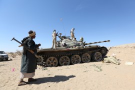 Tribal fighter loyal to Yemen's government walks past an army tank at a position during fighting atainst Houthi rebels in an area between Yemen's northern provoices of al-Jawf and Marib