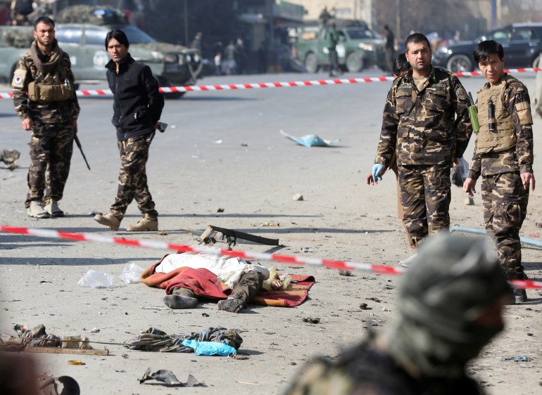 Afghan security forces inspect near a dead body of a victim after an explosion in Kabul