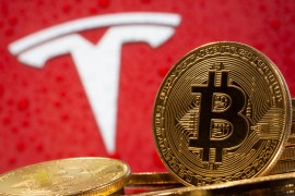 Representations of virtual currency Bitcoin are seen in front of Tesla logo in this illustration