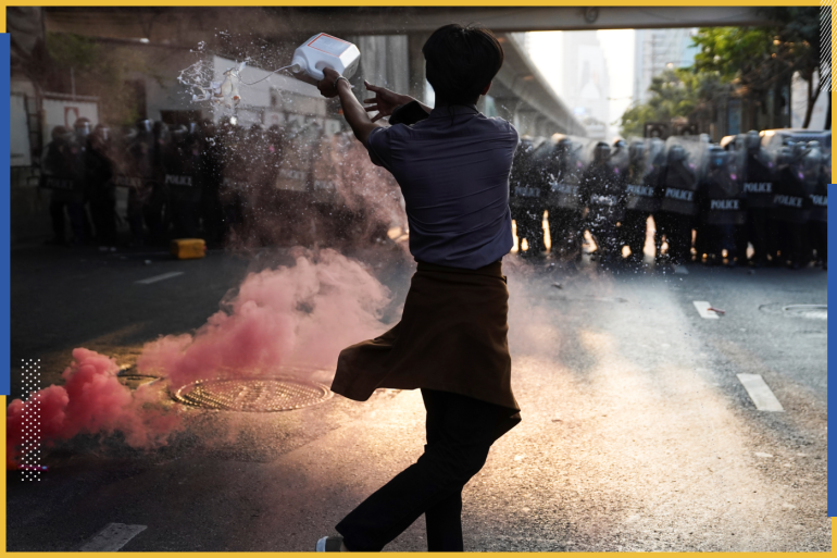 Anti-Thai government protester throws a liquid during a clash with riot police after protesters showed up at a rally for Myanmar's democracy outside the embassy, in Bangkok, Thailand February 1, 2021. REUTERS/Athit Perawongmetha TPX IMAGES OF THE DAY