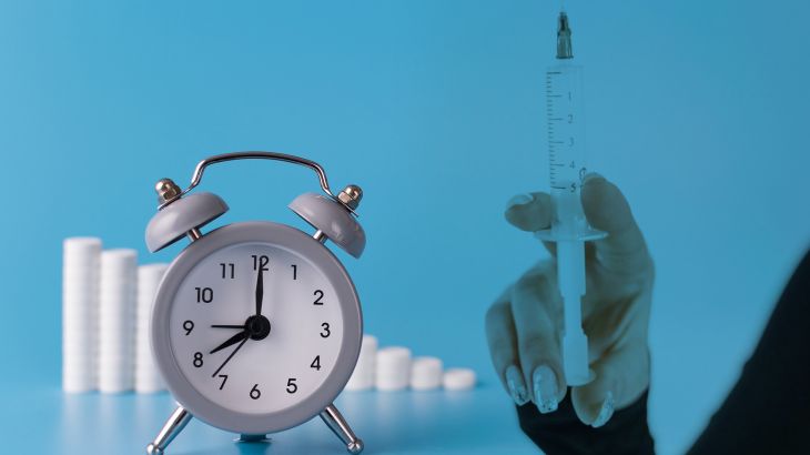 clock with alarm clock stand on a blue background and show the exact time for the taking of medicines next to them; medical talbetas are laid out for the treatment of diseases; Shutterstock ID 1407068831; Department: Creative; Client: Imtyazat; Other: online