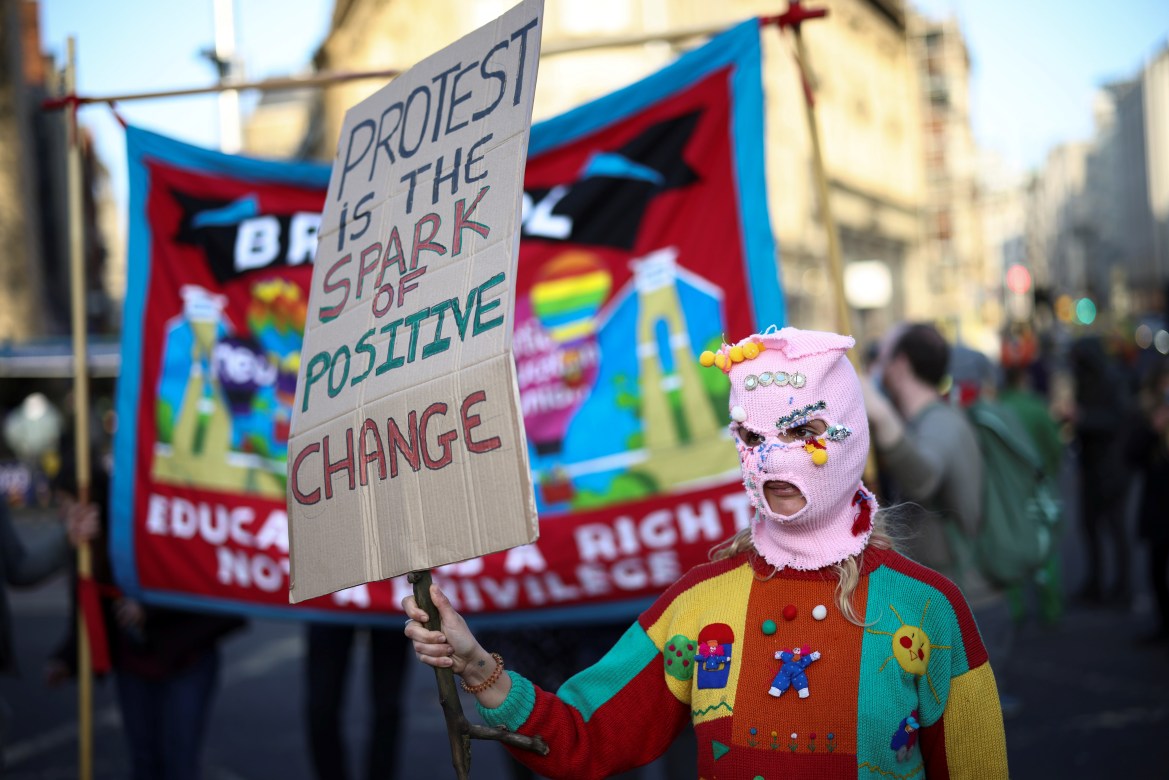 Un manifestant portant un masque dans la ville de Bristol, au sud-ouest de la Grande-Bretagne, tient une pancarte indiquant que "les manifestations parlent d'un changement positif" (Reuters)