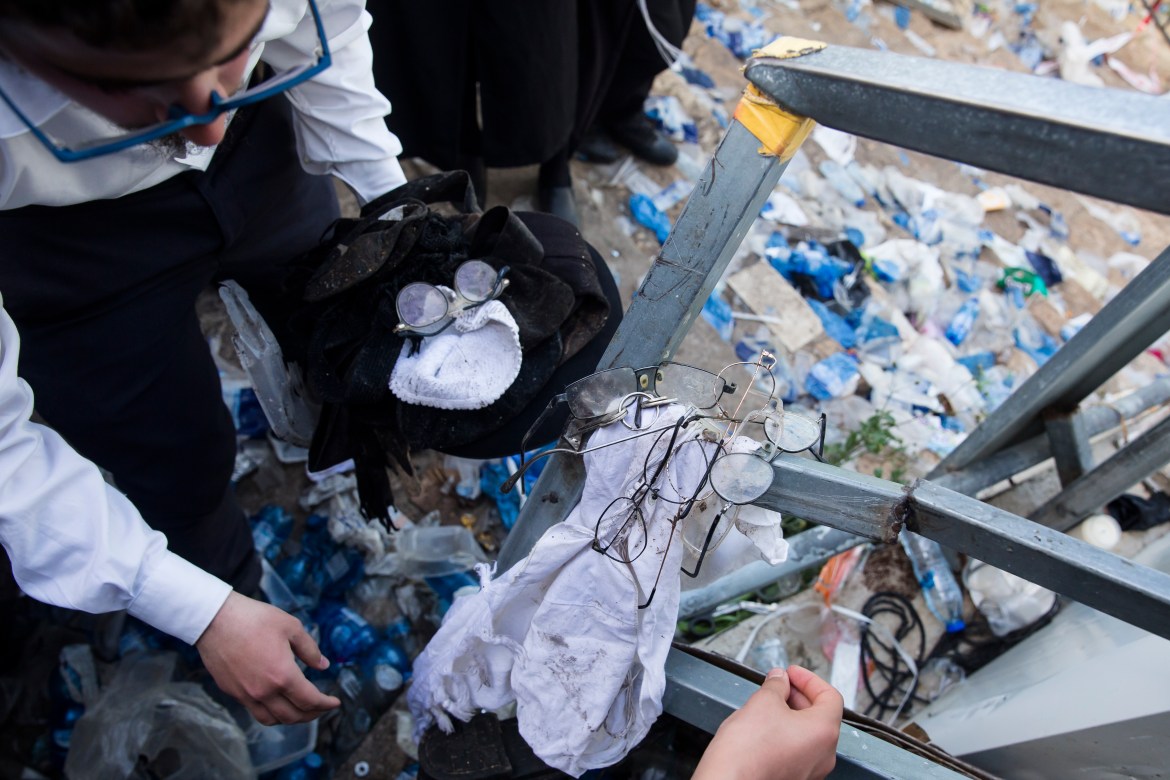 Ultra-Orthodox Jews collect glasses, black hats and other belongings on the ground after dozens were killed in the stampede (Getty Images)