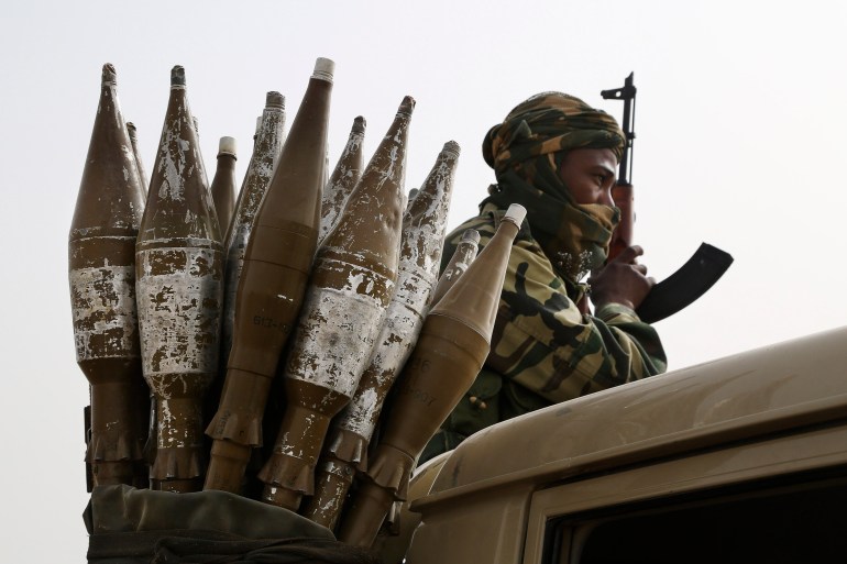 A Chadian soldier rides atop a pickup truck next to a bag of rocket-propelled grenades in Gambaru