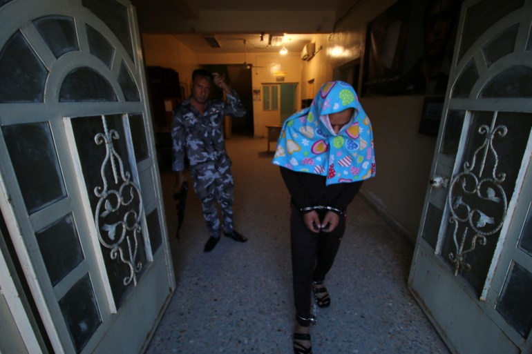 An Iraqi suspect who was arrested for drug-related crimes walks handcuffed at a police station in Basra