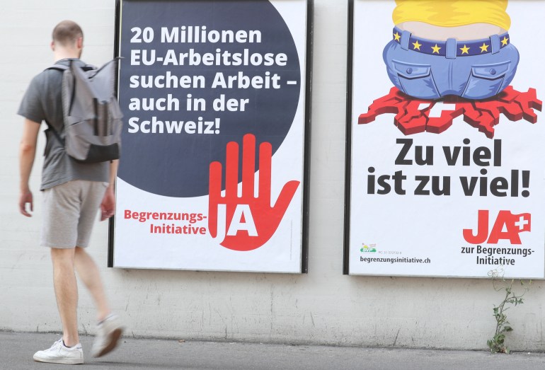 Man walks past posters against the anti-immigration initiative in Zurich