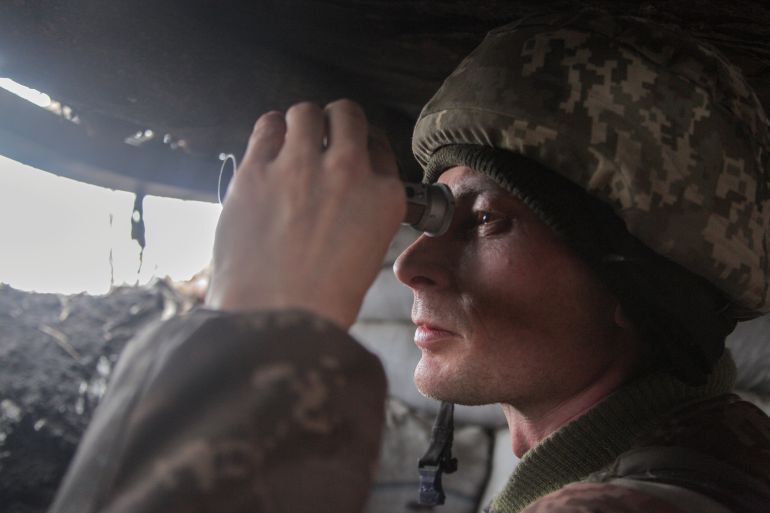 A service member of the Ukrainian armed forces observes the area at fighting positions near the rebel-controlled city of Donetsk