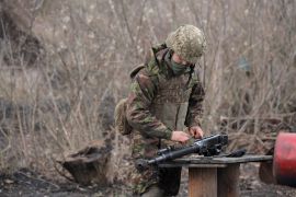 A service member of the Ukrainian armed forces cleans a weapon at fighting positions near the rebel-controlled city of Donetsk