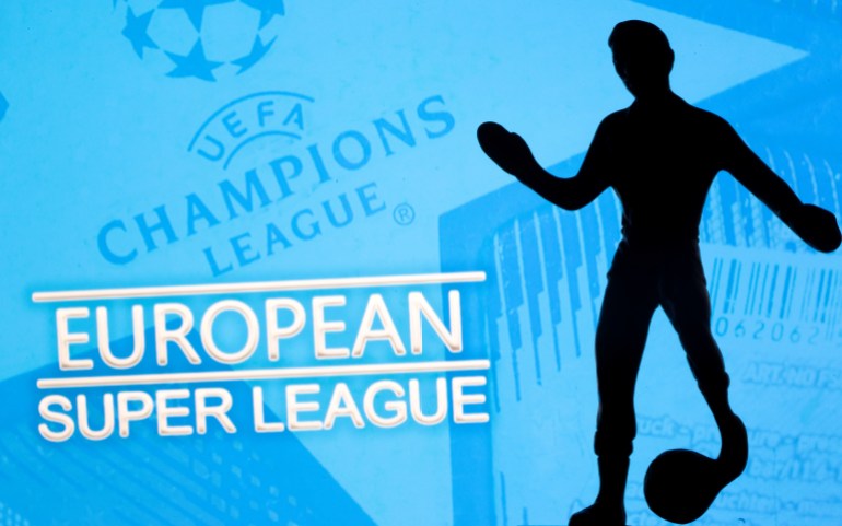 A metal figure of a football player with a ball is seen in front of the words "European Super League" and the UEFA Champions League logo in this illustration A metal figure of a football player with a ball is seen in front of the words "European Super League" and the UEFA Champions League logo in this illustration taken April 20, 2021. REUTERS/Dado Ruvic/Illustration