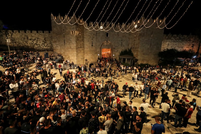 People gather outside Damascus Gate after barriers that were put up by Israeli police are removed, allowing access to the main square that has been the focus of a week of clashes around Jerusalem's Old City