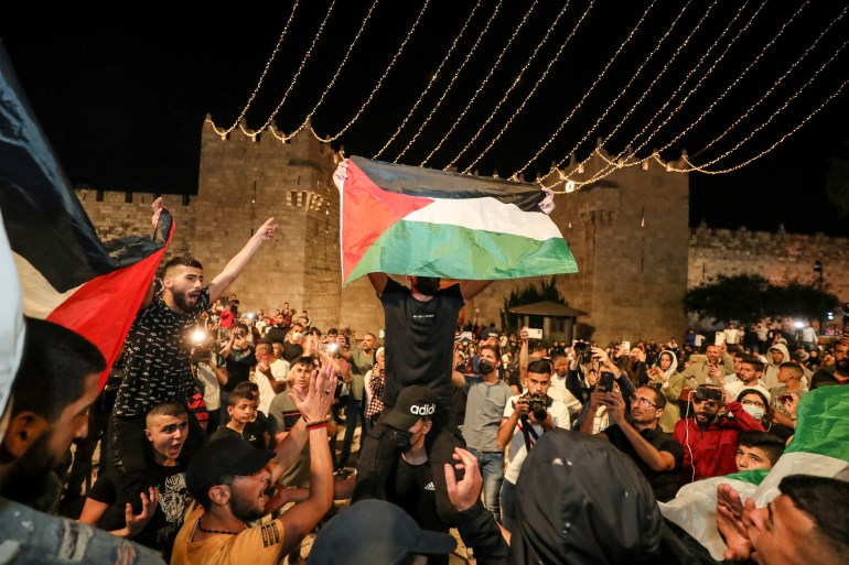 Palestinians wave flags and celebrate outside Damascus Gate after barriers that were put up by Israeli police are removed, allowing them to access the main square that has been the focus of a week of clashes around Jerusalem's Old City