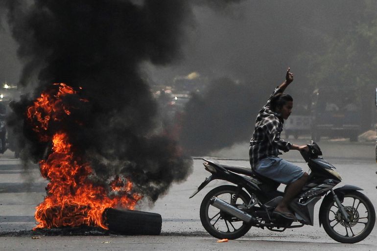 A man flashes the three-finger salute as he passes burning tires during a protest against the military coup, in Mandalay, Myanmar April 1, 2021. REUTERS/Stringer TPX IMAGES OF THE DAY