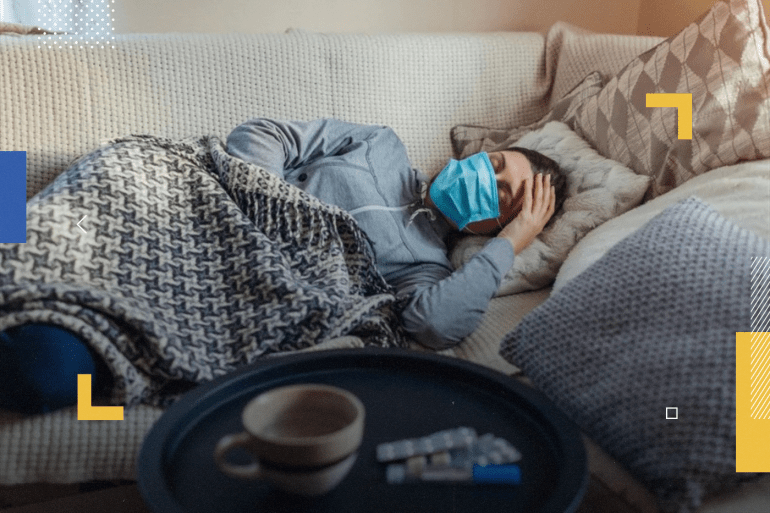 Sick woman having flu or cold. Girl lying in bed wearing protective mask by pills and water on table