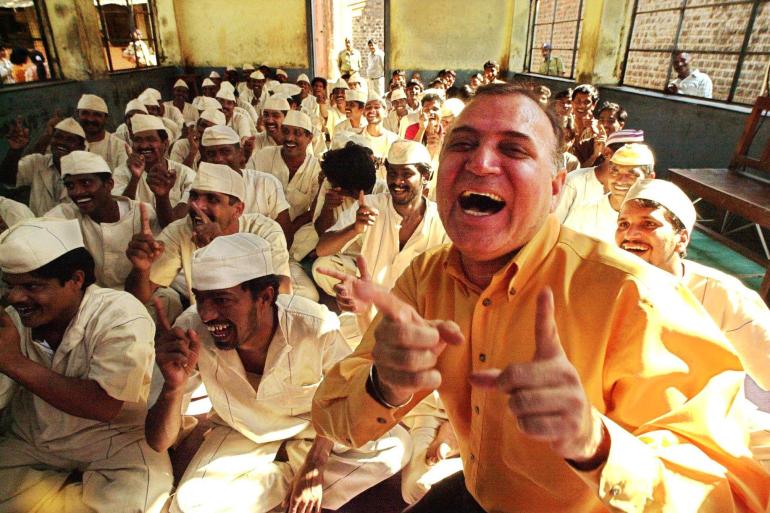 Physician Dr. Madan Kataria (R) leads prisoners in a laughter class at Bombay's biggest Arthur Road jail 19 December 2000 during the filming of a documentary on laughter by the BBC. Kataria is head of the Laughter Club which teaches people the new yogic technique of laughter therapy which benefits the general well-being of participants. AFP PHOTO/Sebastian D'SOUZA (Photo by SEBASTIAN D'SOUZA / AFP)