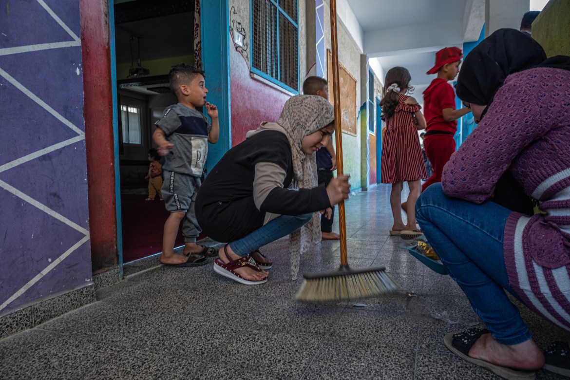 Displaced girls clean the corridor in front of the classroom that houses them at a school they fled to with their families in Gaza (Getty Images)